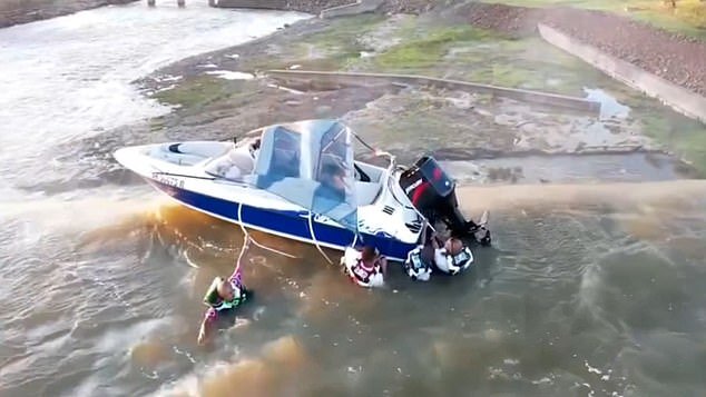 Un momento conmovedor cuando cuatro hombres se aferran a un barco atrapado en el borde de una presa de 130 pies